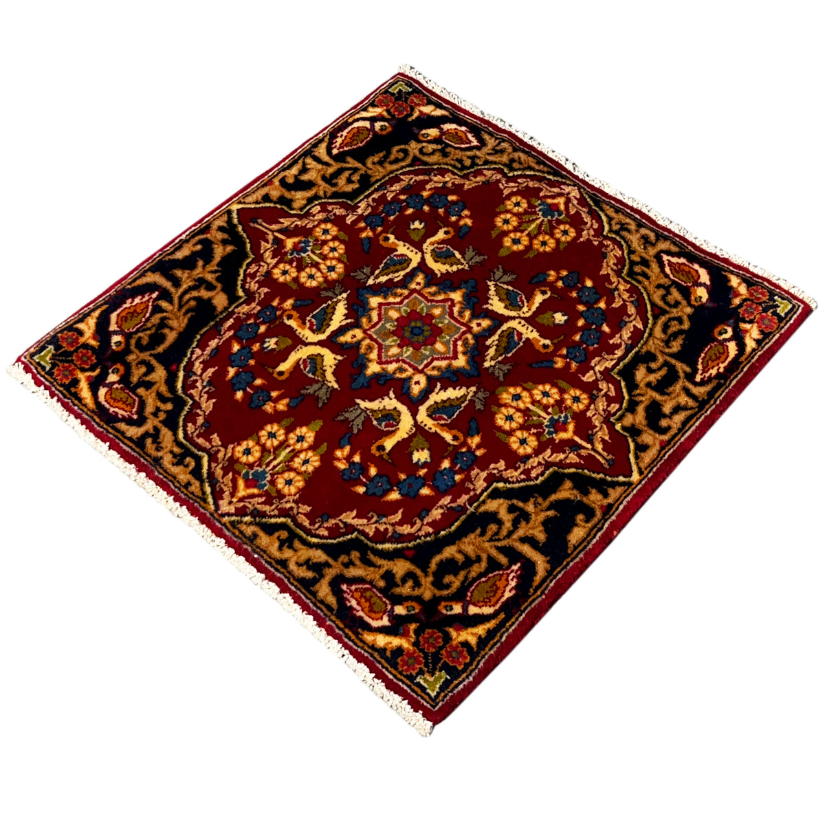 Square rug with a red patterned center and dark blue vines, edged with fringes
