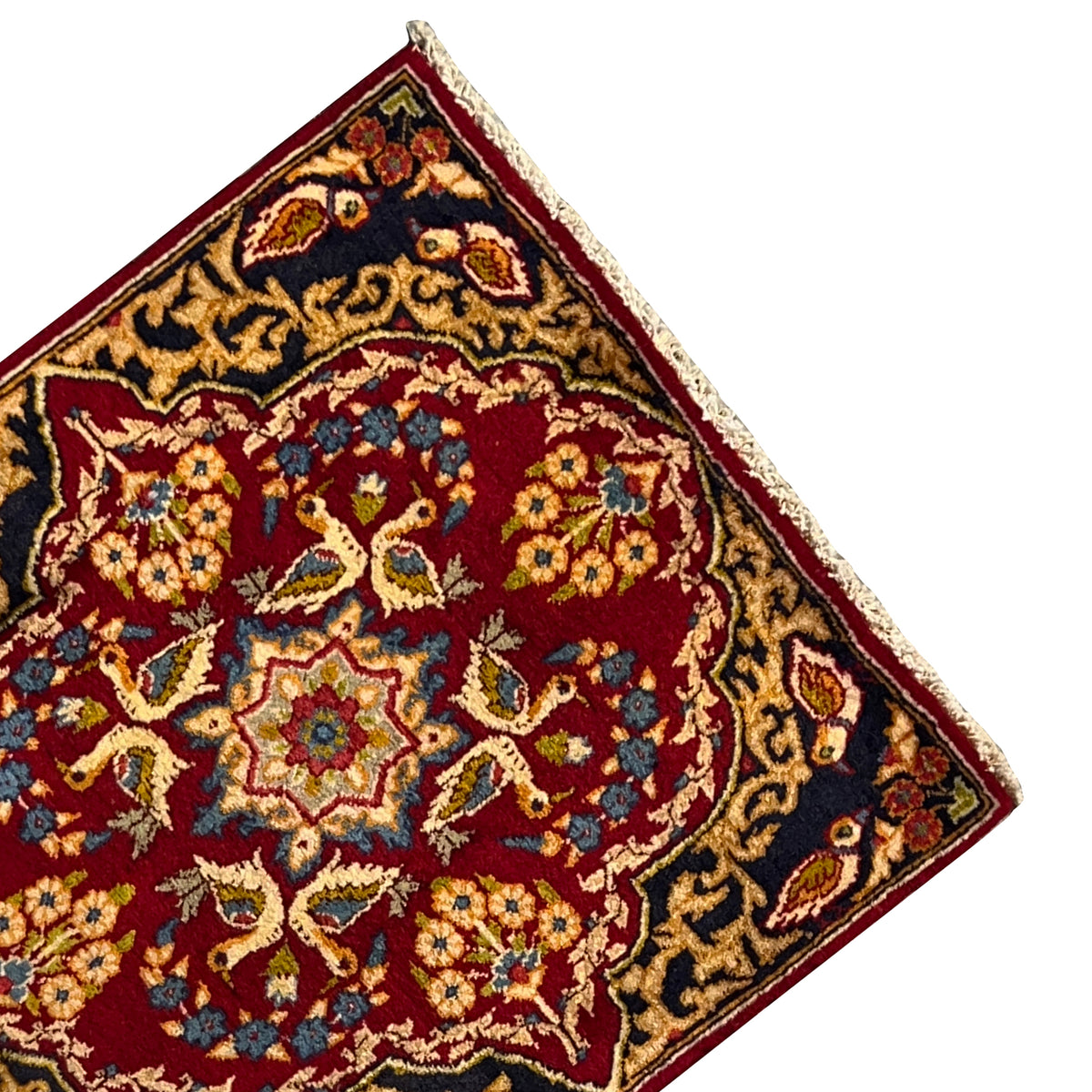 Close-up of carpet: red medallion with blue-and-gold floral ornaments, dark border, fringes