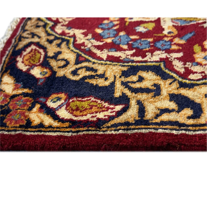 Close-up of a carpet edge: dark blue background with golden vines, red border, fine texture