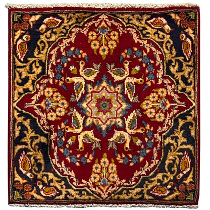 Red-and-black square rug with an ornamental pattern, golden accents, and fringes