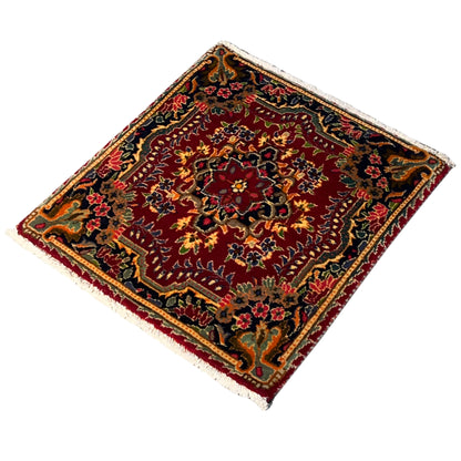 Square red rug viewed diagonally with colorful medallion ornament and decorative border