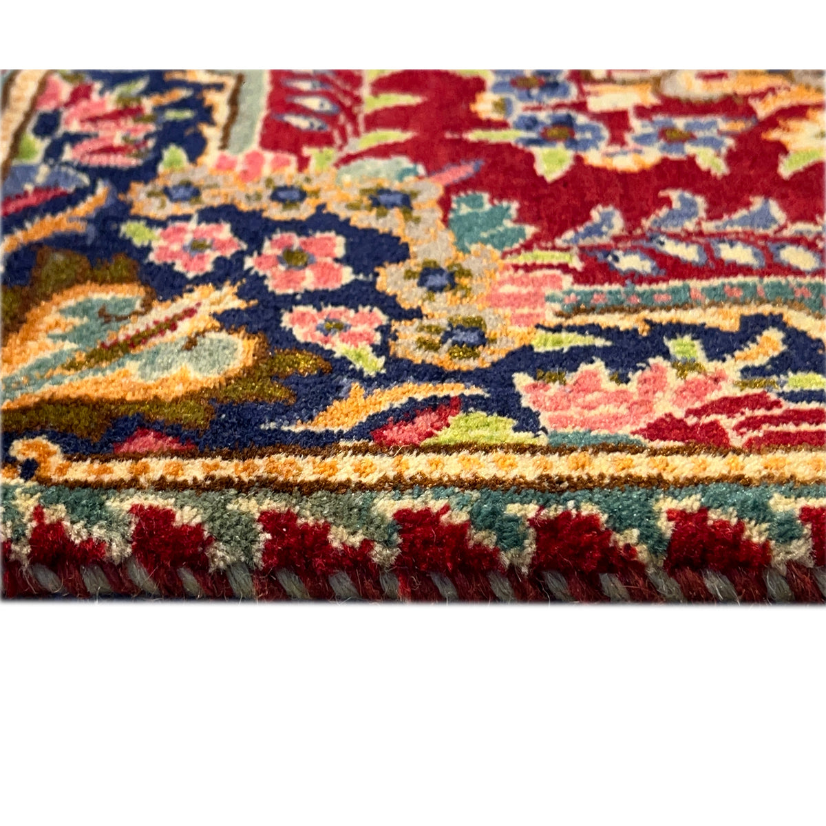 Close-up: multicolored rug pattern on a red background, side edge with fringe