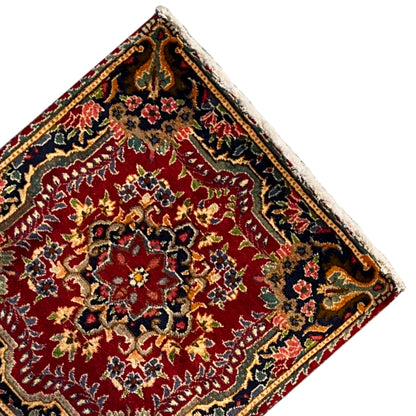 Corner view of a red carpet with colorful ornaments and a bordered edge design