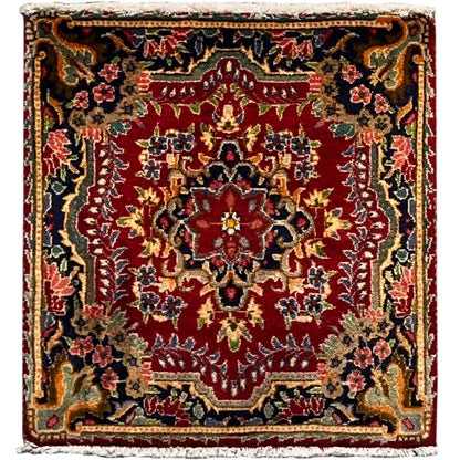 Square red rug with a multicolored ornamental pattern and a wide decorative border