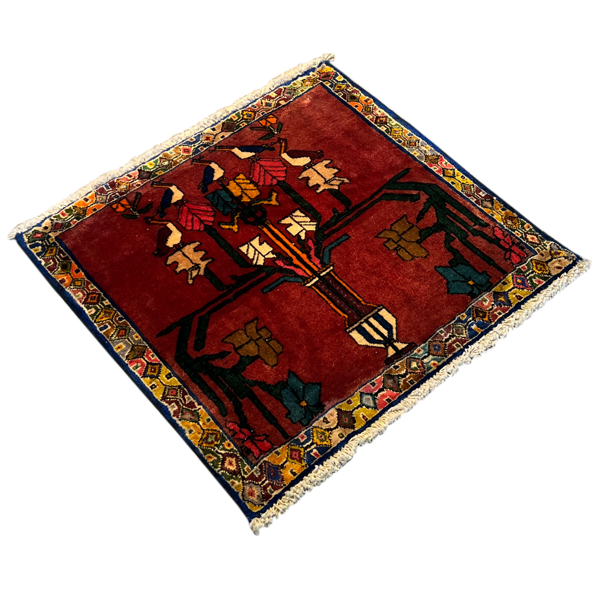 Rectangular rug with a red background and colorful oriental pattern, photographed diagonally, fringes