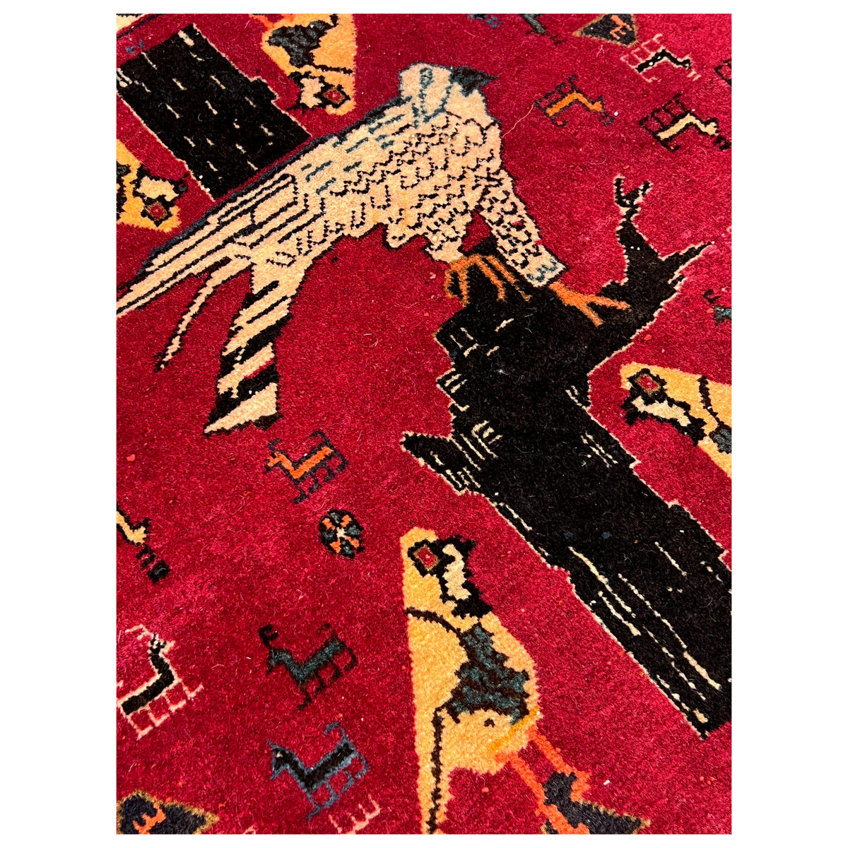 Close-up of a red Poshti carpet: black and yellow animal figures in the pattern