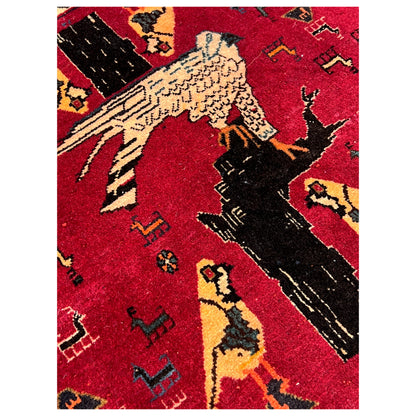 Close-up of a red Poshti carpet: black and yellow animal figures in the pattern
