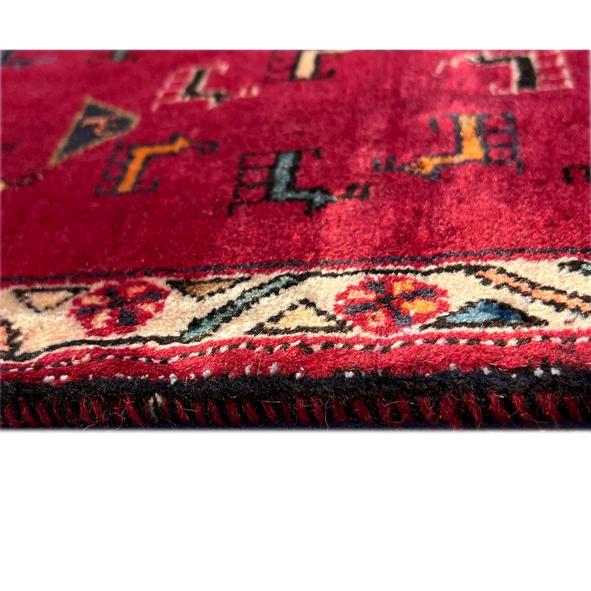 Detail at the edge: red carpet border with multicolored trim and fringe
