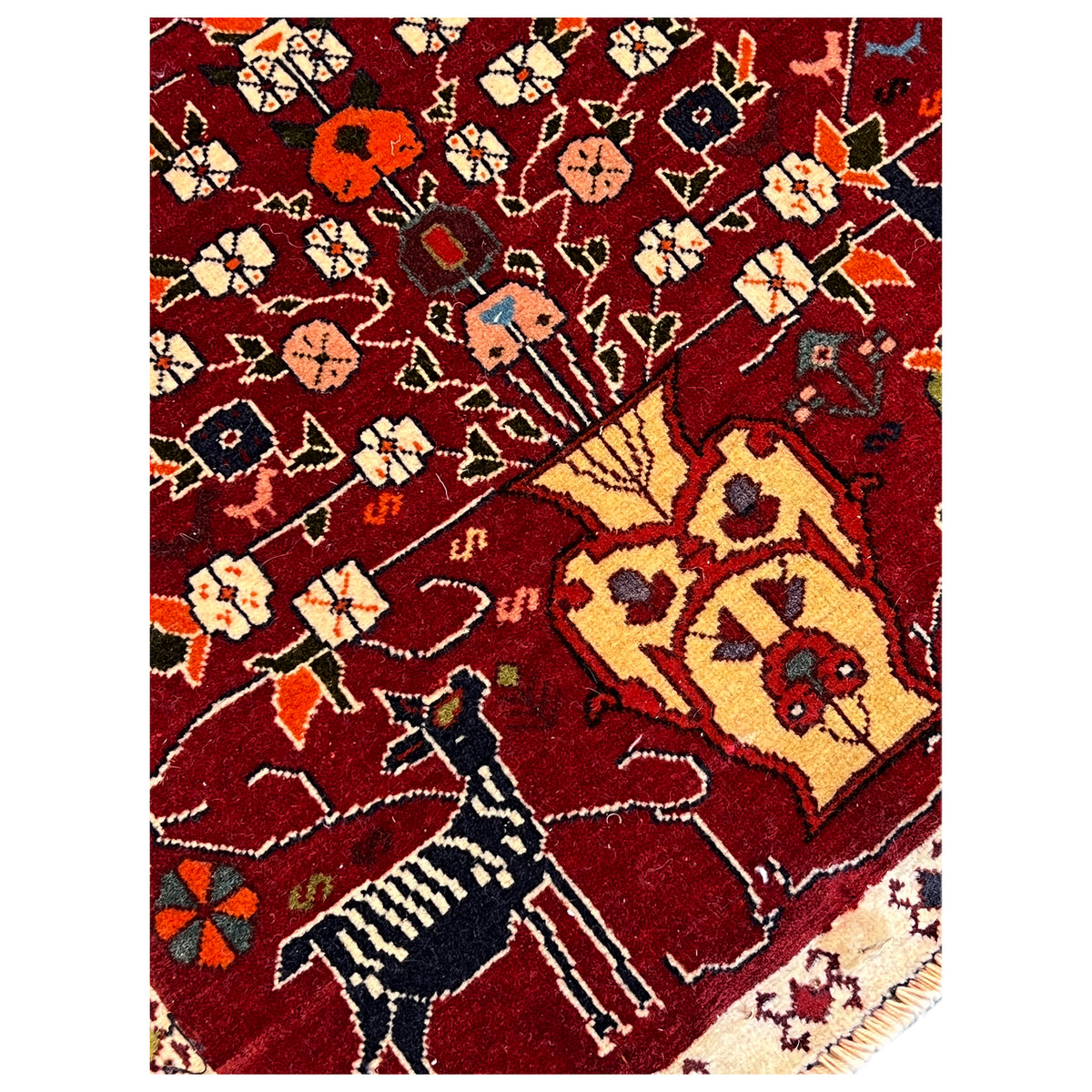 Close-up of the red Poshti rug with ornamental motifs, colorful accents, and a border