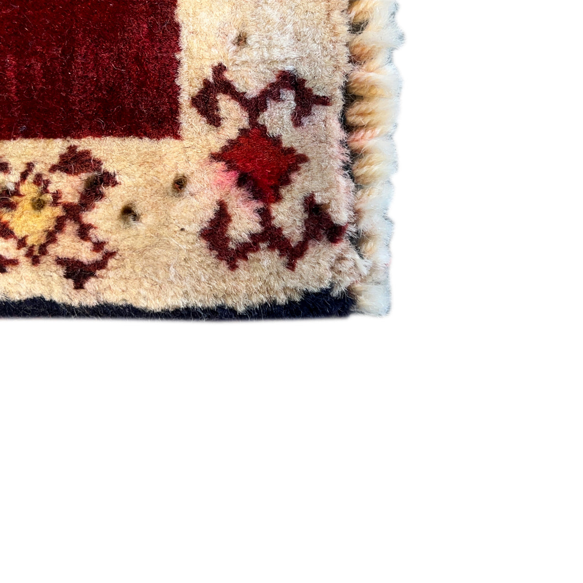 Close-up detail: beige carpet edge with dark ornaments and side fringes