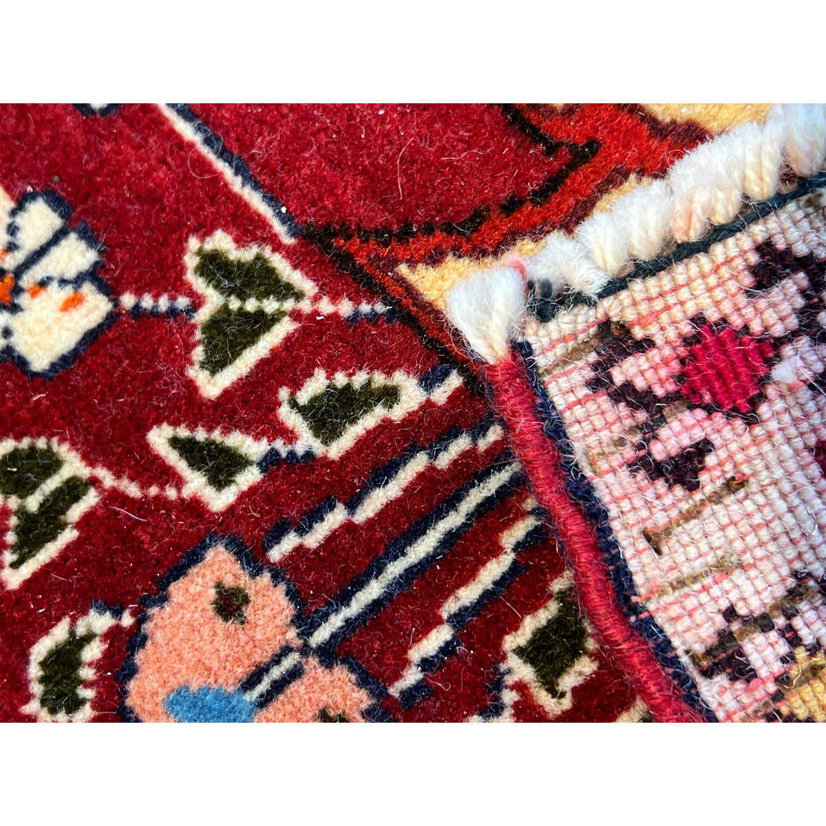 Edge detail of the red carpet with a woven texture, red and beige patterns, and a border