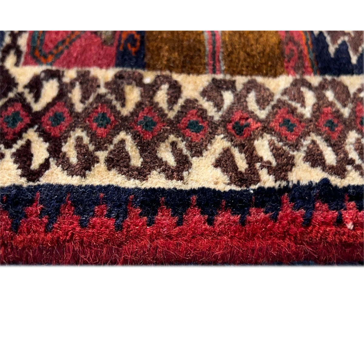 Close-up of the carpet edge with fringes in red and a cream-colored patterned stripe