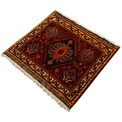Carpet in a diagonal view: red field with geometric motifs and a wide decorative border