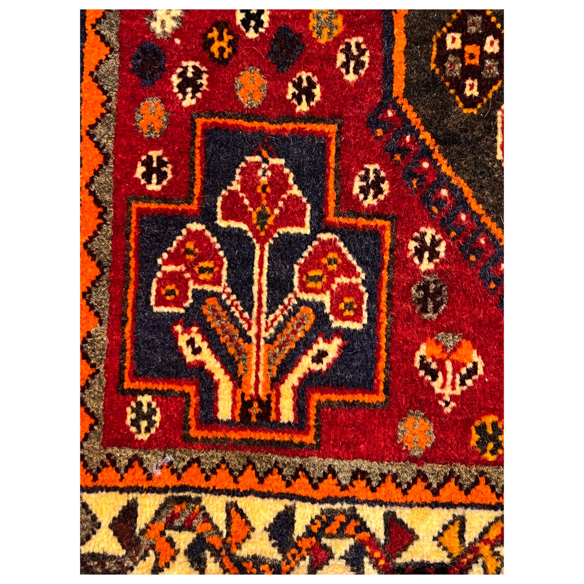 Rug detail: floral ornament with yellow-orange accents on a red background