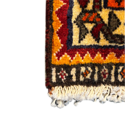 Rug corner with fringes: colorful decorative pattern along the edge, beige pile, and textured hem