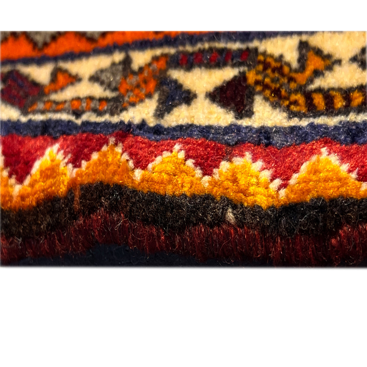 Close-up of a carpet edge with a multicolored border and a dense, crimped-looking pile edge