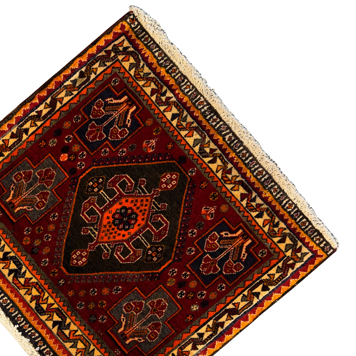 Top view of a carpet detail: red central medallion with geometric motifs and an ornamental frieze