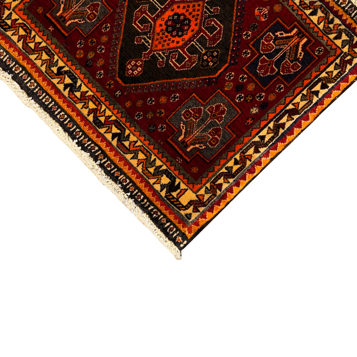 Rug corner view: red patterned field, beige border band, and black zigzag elements