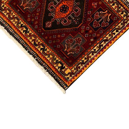 Rug corner view: red patterned field, beige border band, and black zigzag elements