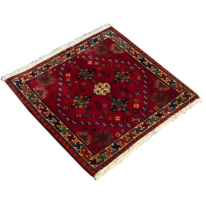 Red Poshti rug in detail with a gold-colored ornamental motif, multicolored border, and fringes