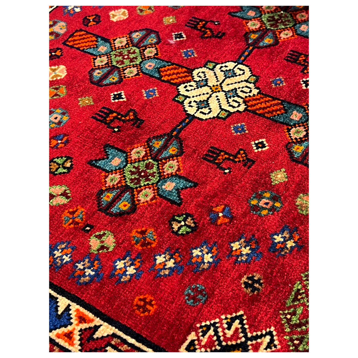 Close-up of a red Poshti rug with colorful, tile-like ornaments and a central motif