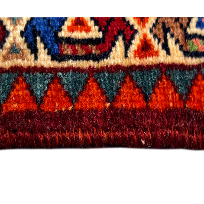 Close-up of a sample area of a red Poshti rug with multicolored sections and edge