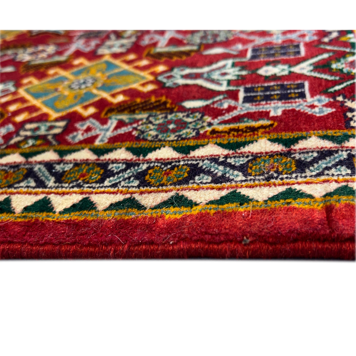 Close-up: red carpet with multicolored ornaments and a woven edge