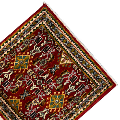 Corner of a rug with a red ornamental field, yellow-green border, and fringe