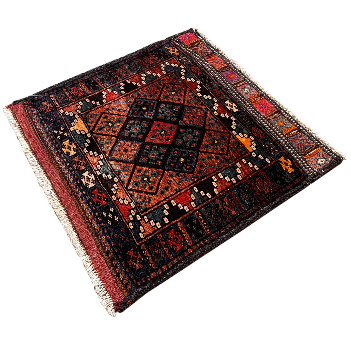 Hamedan Poshti rug at an angle: dark ornamental pattern with red accents, fringes on both sides