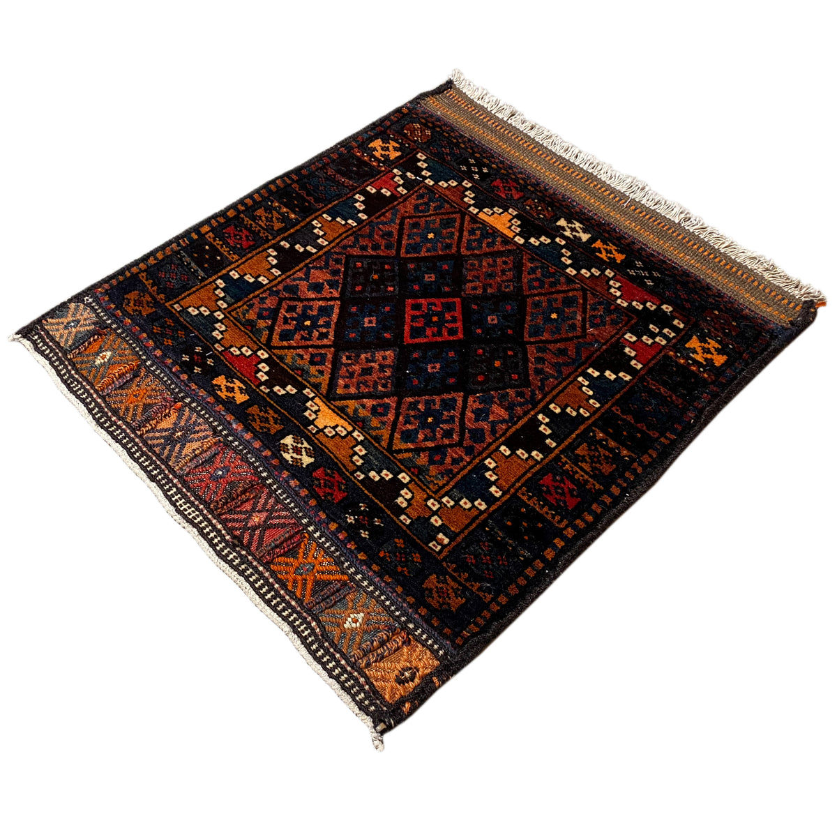 Rug in dark colors with a geometric central motif, decorative borders, and fringes