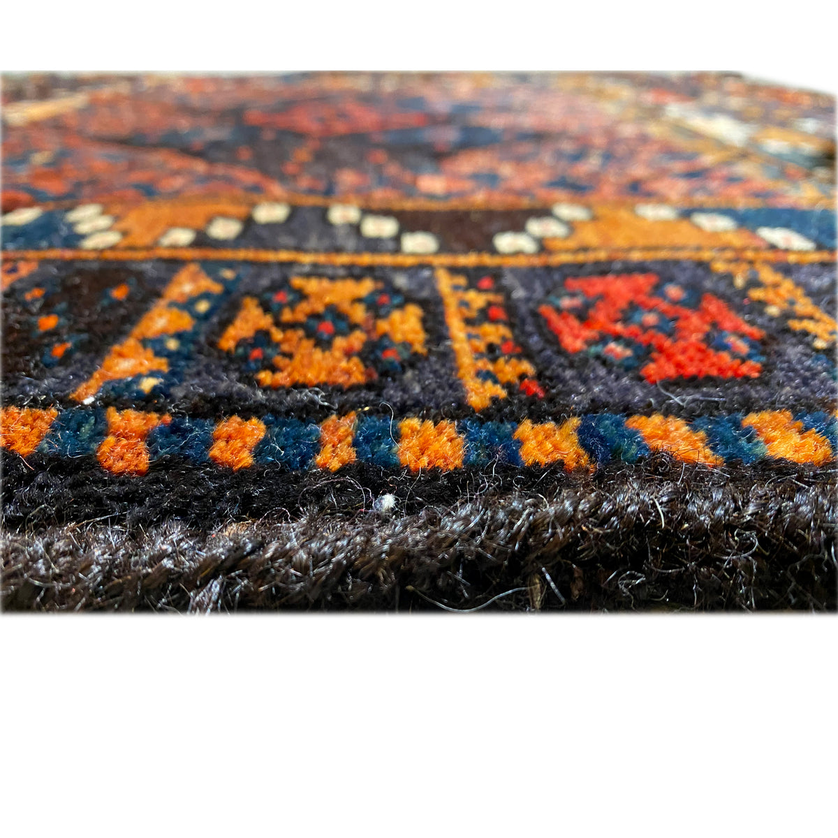 Carpet detail of the pile height with a dark pattern and colorful accents in blue and orange