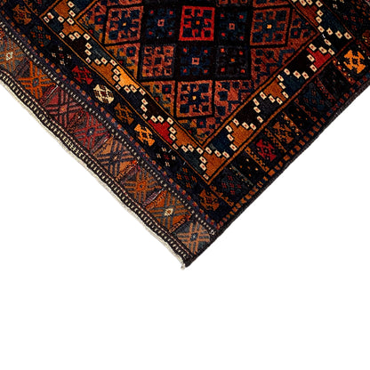 Rug corner with a dark pattern, border, and fringed edges, with red and orange accents