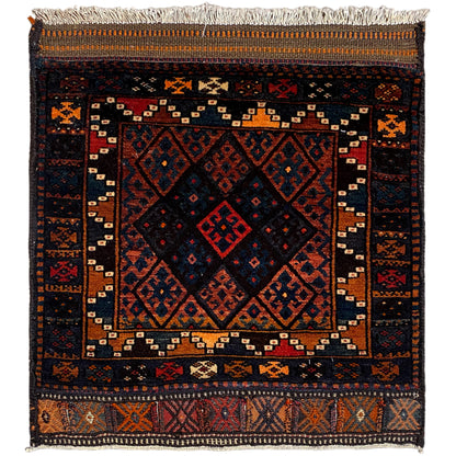Rug with a dark background, geometric pattern in shades of red, blue, and orange, fringes