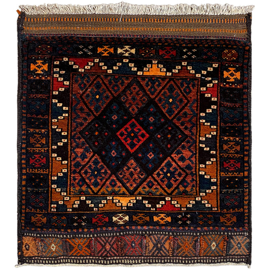 Rug with a dark background, geometric pattern in shades of red, blue, and orange, fringes
