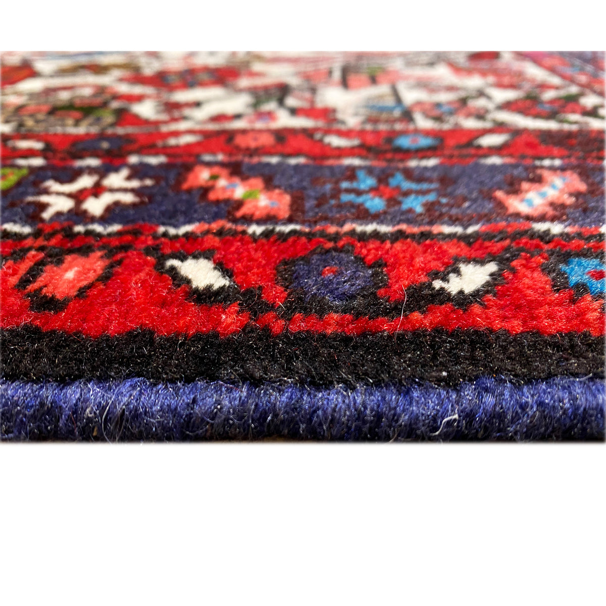 Rug edge with dense pile, patterned in red and blue, contrasting color stripes