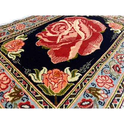 Close-up of Hamedan Poshti rug: red rose motif on a black background, multicolored floral borders.