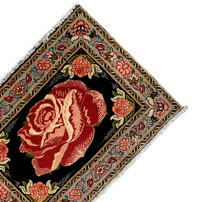 Hamedan Poshti carpet detail from above: black center with a red rose and decorative borders.