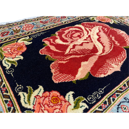 Hamedan Poshti rug close-up: red rose motif on a black background, colorful flowers along the border.