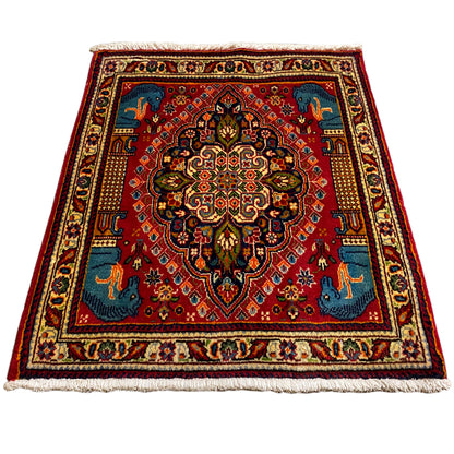 Square rug, red background with a blue pattern and animal motifs, wide cream border