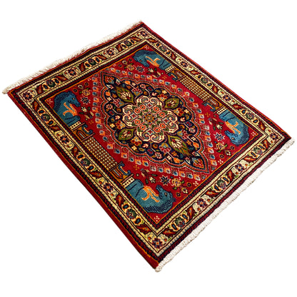 Rug in diagonal view: red field, blue corner decoration, central ornament, and animal motifs
