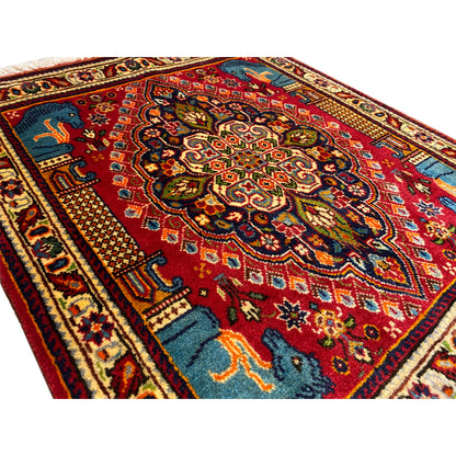 Detailed view of the rug: red ornamental field, blue animals, multicolored border, dense pile