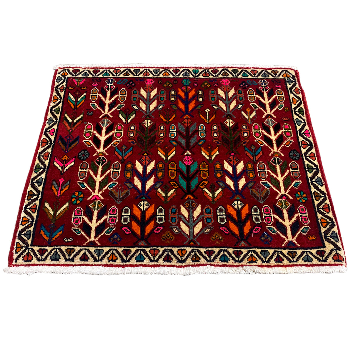 Rug with a red background and multicolored ornaments, framed by a zigzag border.