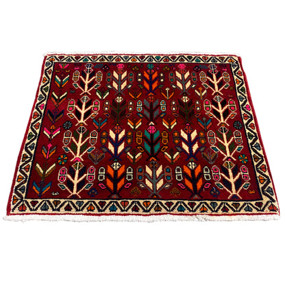Rug with a red background and multicolored ornaments, framed by a zigzag border.