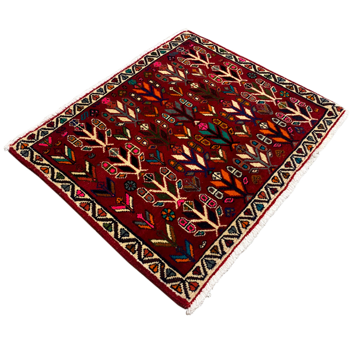 Rug, photographed diagonally: red field with trees, diamonds, and colorful details.