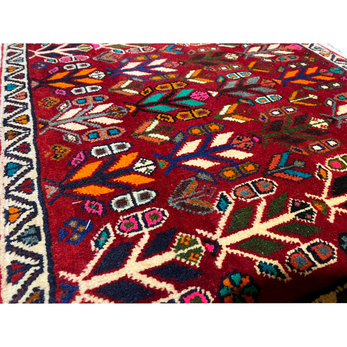 Close-up of the carpet pattern: red background with colorful diamonds, crosses, and tree ornaments.