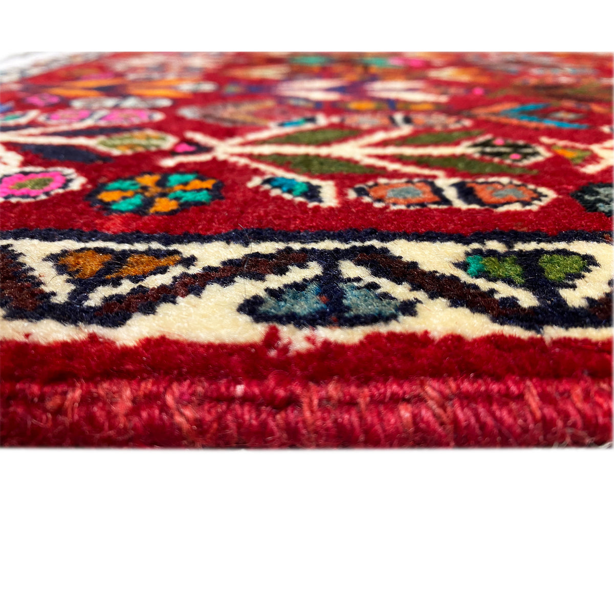 Carpet pile and border: short red pile with colorful patterned elements and a finished edge.