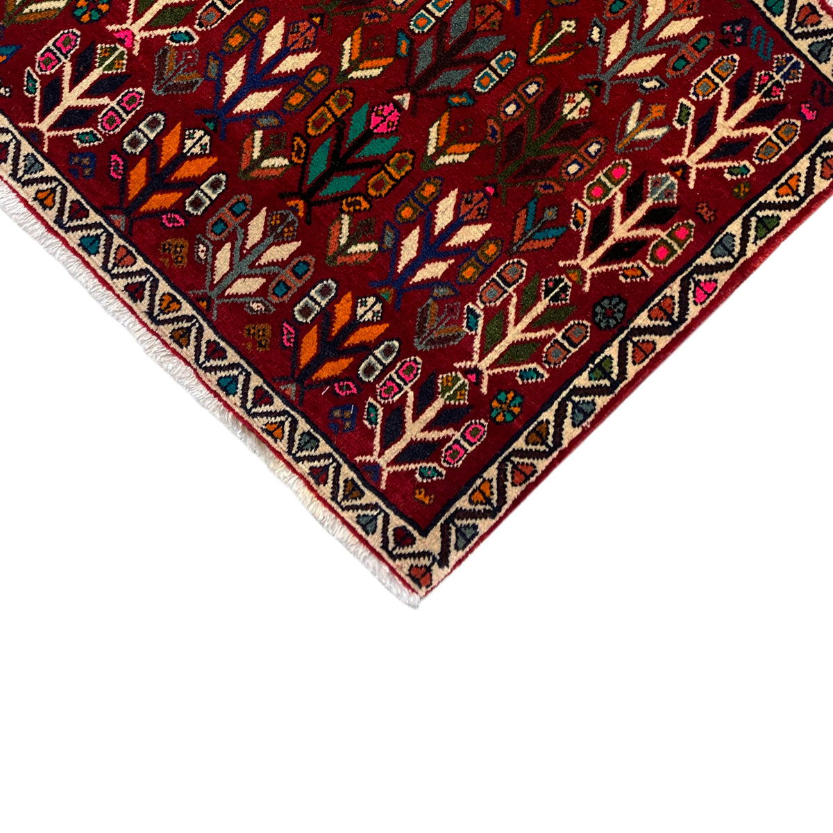 Carpet corner with border: red patterned field with tree ornaments and a multicolored zigzag edge.