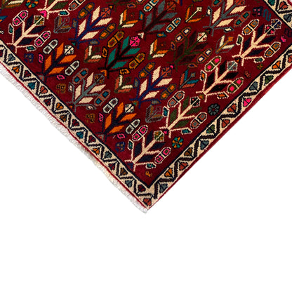 Carpet corner with border: red patterned field with tree ornaments and a multicolored zigzag edge.