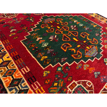 Detail of the carpet: red field with green-yellow ornaments and decorative borders along the edge