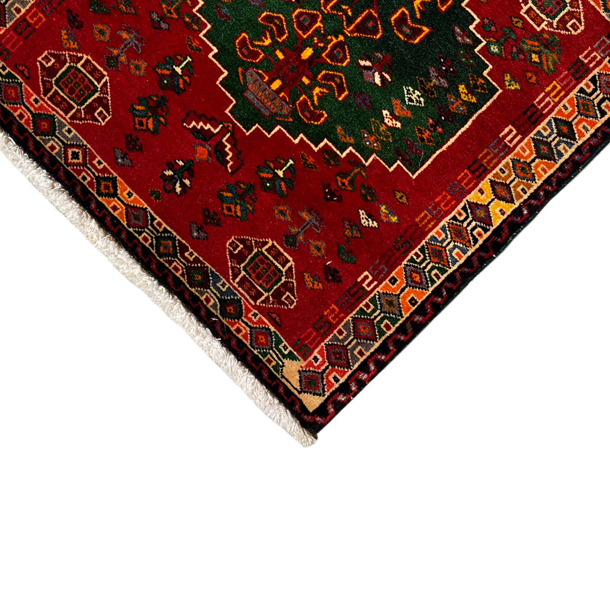 Close-up detail of the carpet: red patterned area with decorative border and white fringes